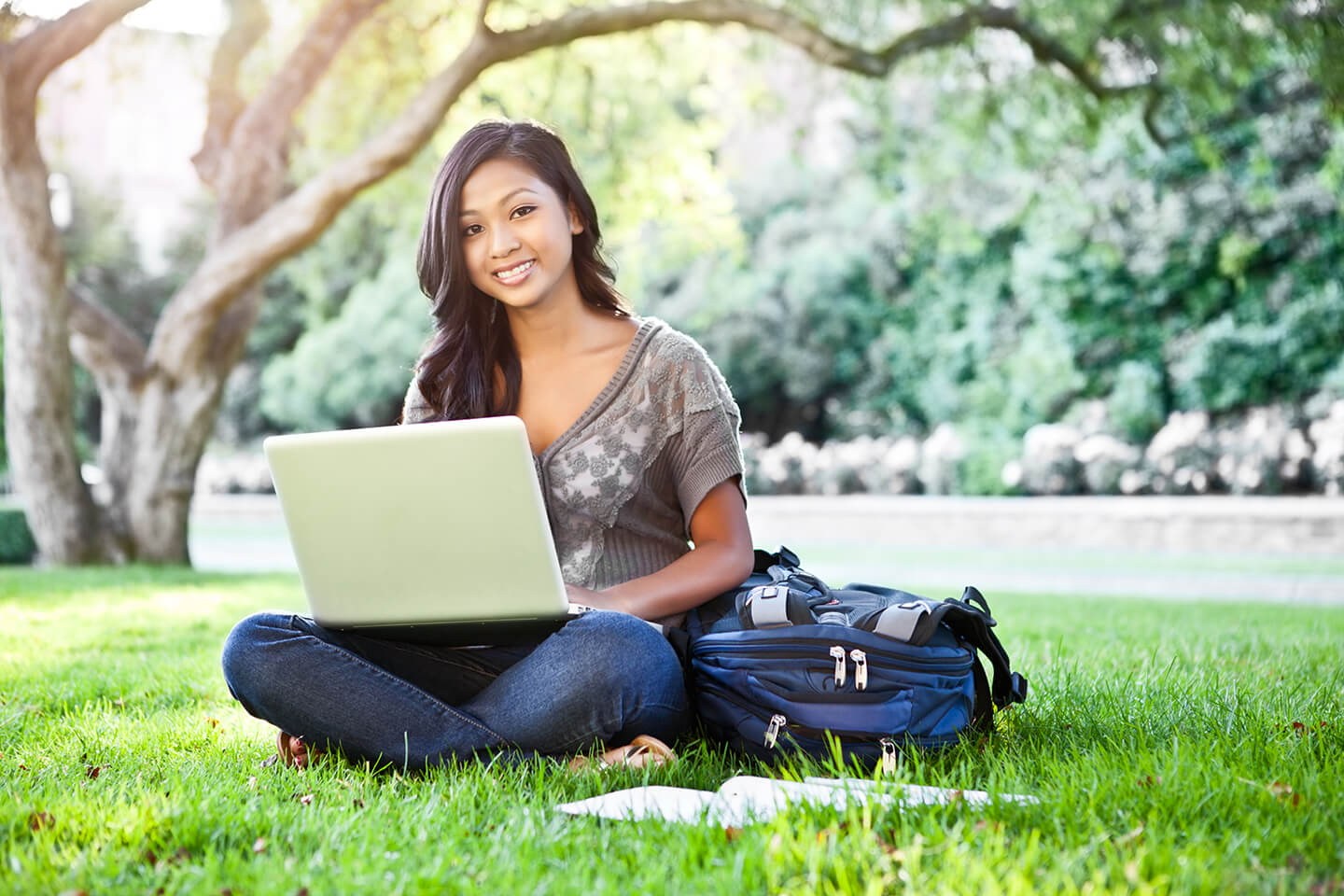 Student sitting on the grass with a laptop